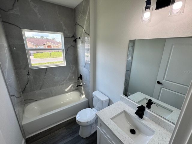 full bathroom featuring tiled shower / bath, vanity, hardwood / wood-style floors, and toilet