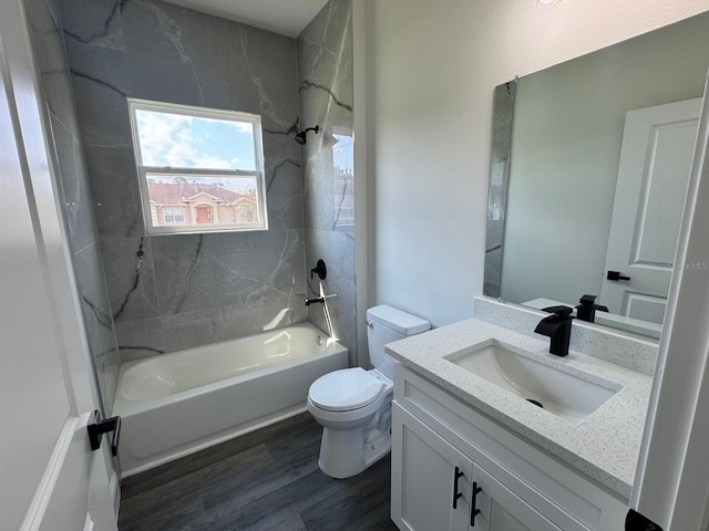 full bathroom featuring hardwood / wood-style floors, vanity, tiled shower / bath combo, and toilet