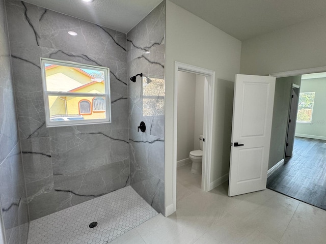 bathroom with hardwood / wood-style floors, a tile shower, and toilet