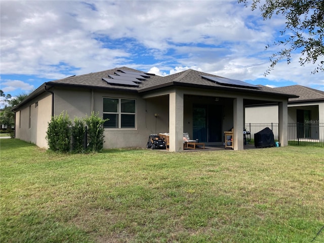 rear view of house with a lawn, solar panels, and a patio