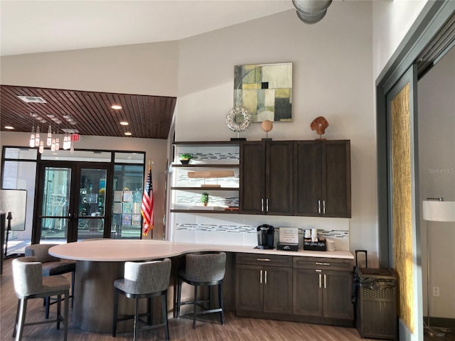 bar with dark brown cabinets, vaulted ceiling, and dark hardwood / wood-style flooring