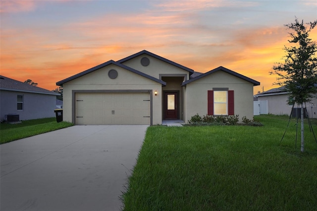 single story home featuring a lawn, central AC unit, and a garage