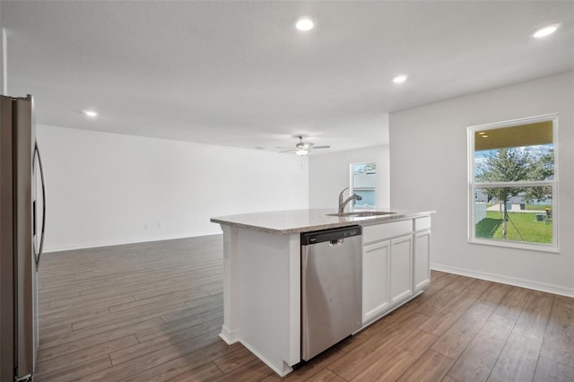 kitchen with white cabinets, stainless steel appliances, light wood-type flooring, ceiling fan, and a center island with sink