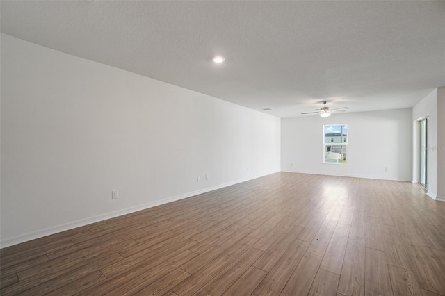 unfurnished living room featuring ceiling fan, hardwood / wood-style floors, and a textured ceiling