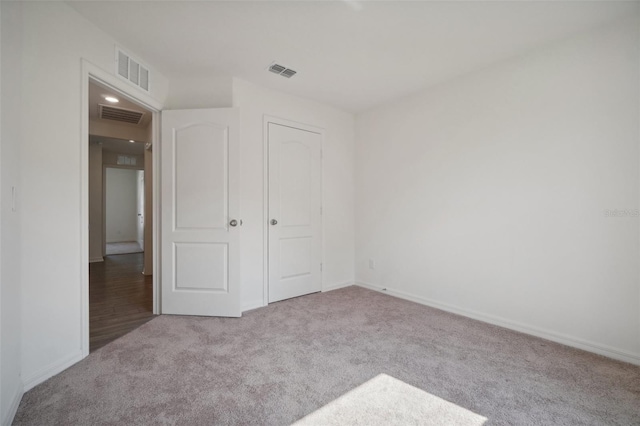 unfurnished bedroom featuring light carpet and a closet