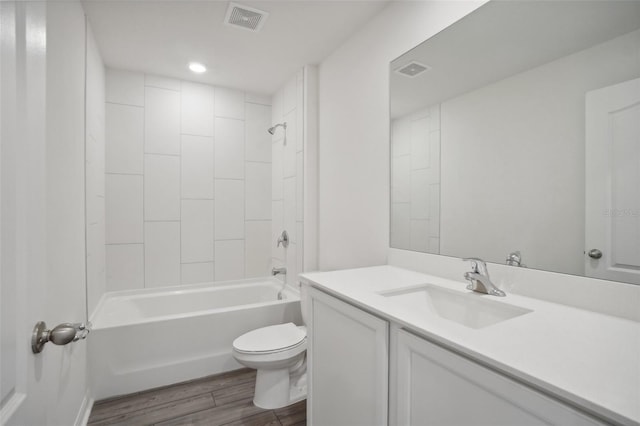 full bathroom with vanity, tiled shower / bath, hardwood / wood-style flooring, and toilet