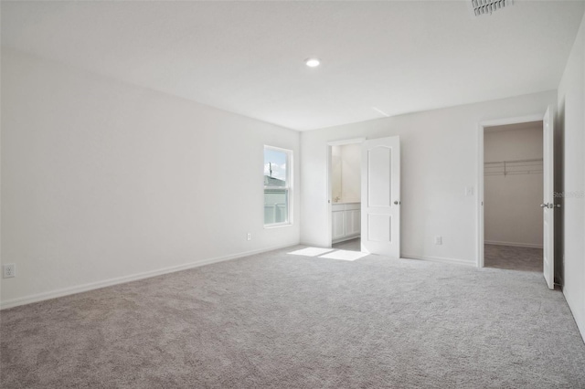 unfurnished bedroom featuring light carpet, a walk in closet, and a closet