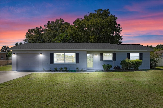 ranch-style house with a garage and a yard