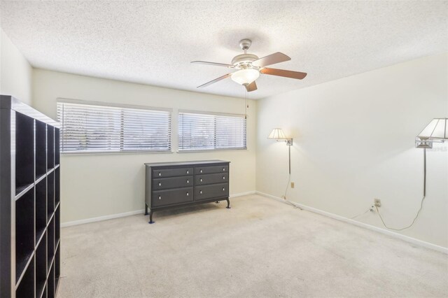 bedroom featuring ceiling fan, light carpet, and a textured ceiling