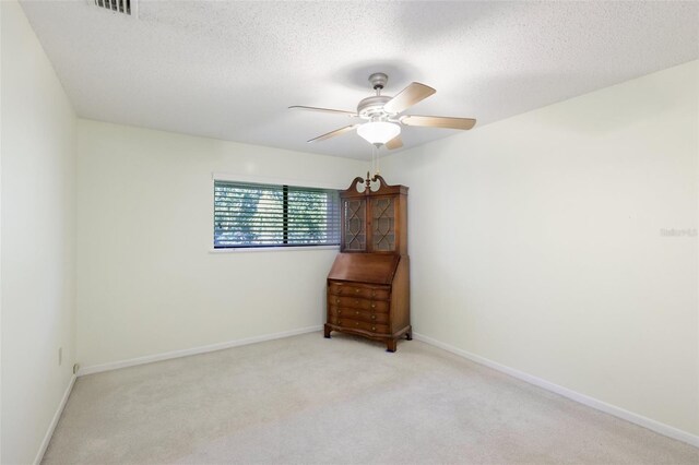 spare room with light carpet, a textured ceiling, and ceiling fan