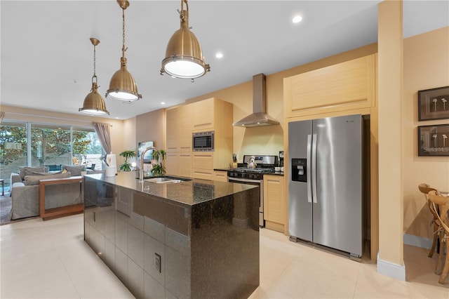 kitchen with a kitchen island with sink, sink, wall chimney range hood, light brown cabinets, and appliances with stainless steel finishes