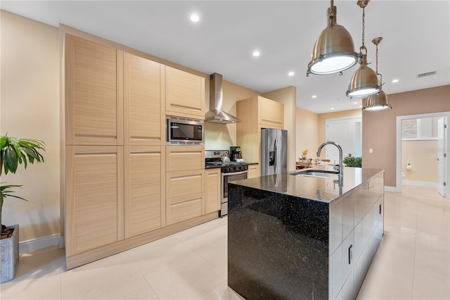 kitchen with appliances with stainless steel finishes, hanging light fixtures, wall chimney exhaust hood, a kitchen island with sink, and sink