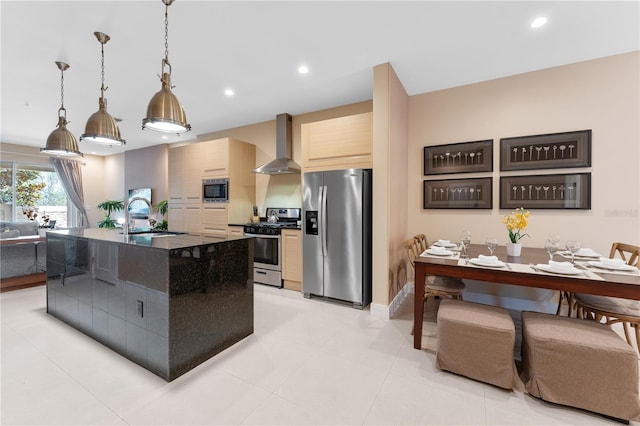 kitchen featuring pendant lighting, an island with sink, sink, wall chimney exhaust hood, and stainless steel appliances