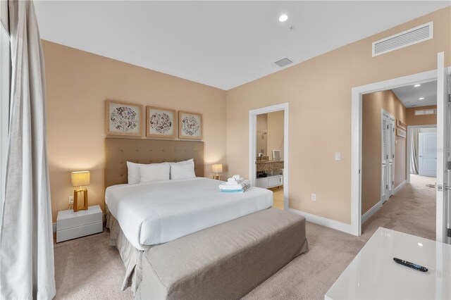 bedroom with light carpet and ensuite bath