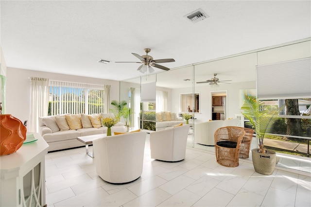 living room featuring ceiling fan and a textured ceiling