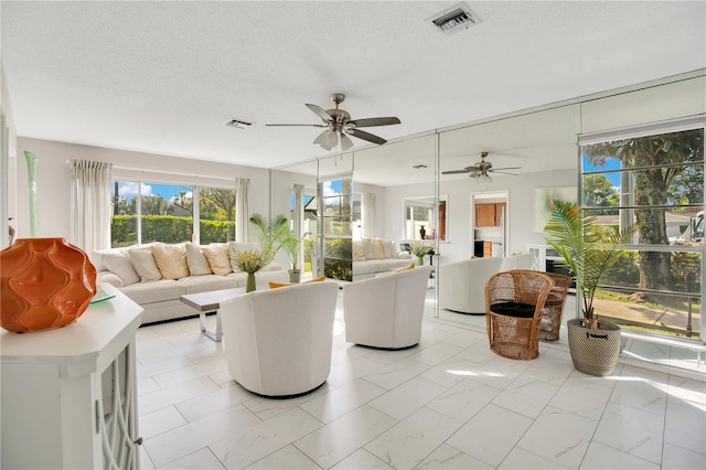 living room featuring ceiling fan and a textured ceiling