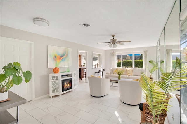 living room with ceiling fan and a textured ceiling