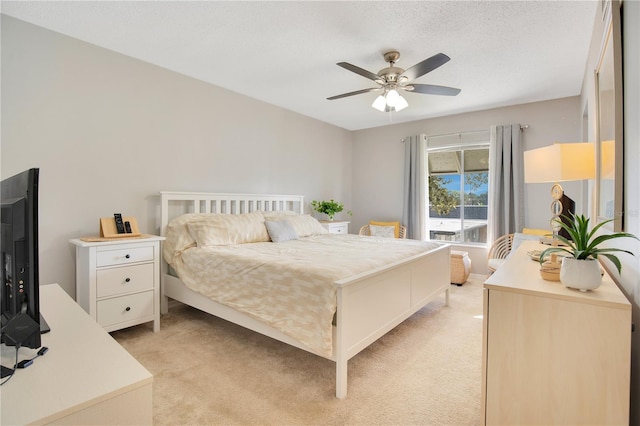 bedroom with ceiling fan, light colored carpet, and a textured ceiling