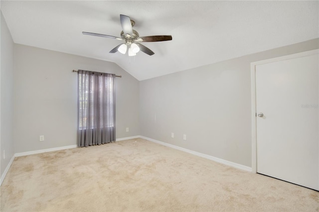 spare room featuring lofted ceiling, ceiling fan, and light colored carpet