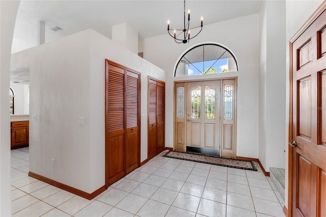 tiled foyer entrance with a towering ceiling and an inviting chandelier