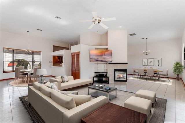 tiled living room with a fireplace and ceiling fan with notable chandelier