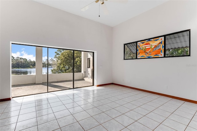 tiled spare room with a high ceiling, a water view, and ceiling fan