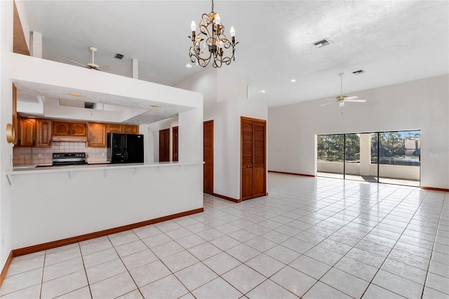 kitchen featuring a towering ceiling, black appliances, hanging light fixtures, and light tile patterned floors