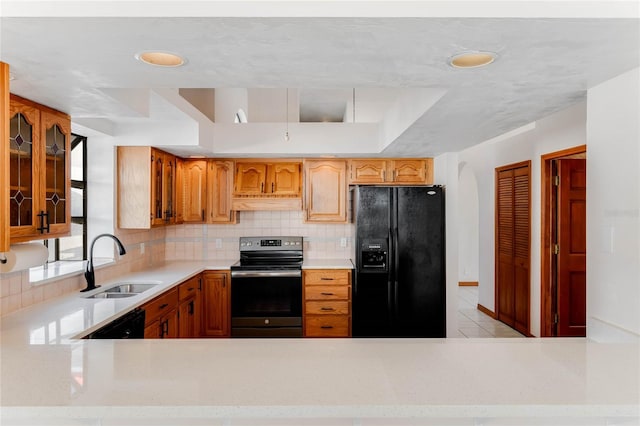 kitchen with custom exhaust hood, kitchen peninsula, decorative backsplash, black appliances, and sink