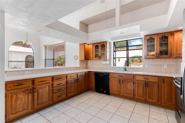 kitchen featuring black dishwasher, tasteful backsplash, sink, and a tray ceiling