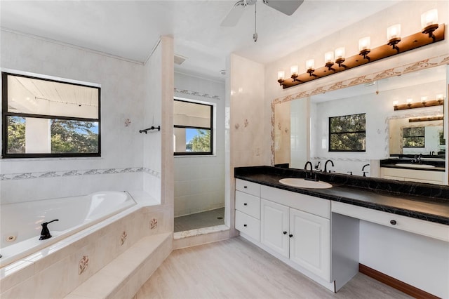 bathroom with vanity, ceiling fan, a healthy amount of sunlight, and plus walk in shower