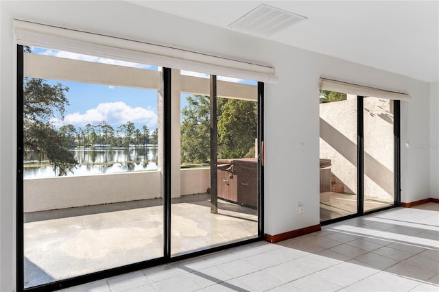 doorway to outside featuring a water view and light tile patterned floors