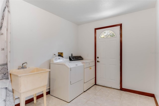 laundry area with sink, washing machine and dryer, and light tile patterned floors