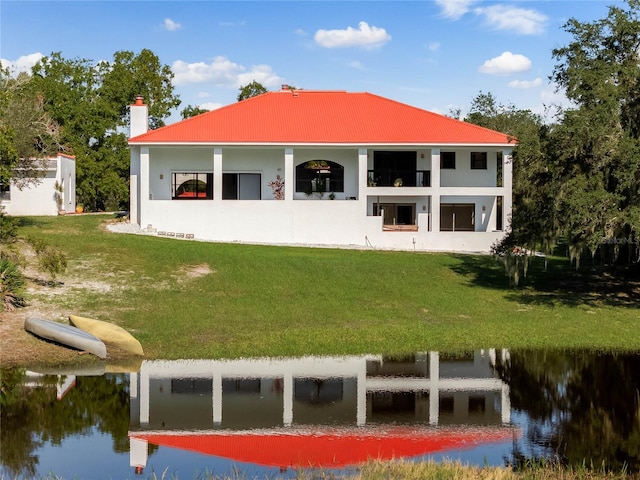 back of property with a yard and a water view