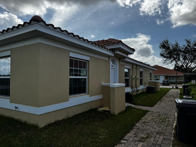 view of property exterior with a lawn and central AC