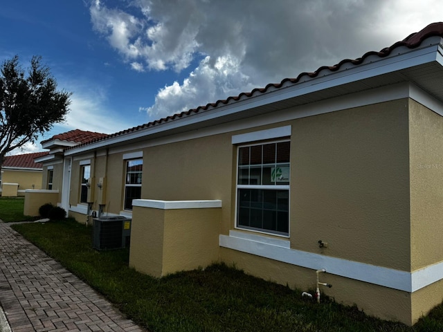 view of property exterior with a lawn and central AC