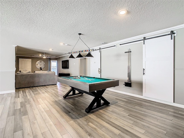 rec room with a textured ceiling, hardwood / wood-style flooring, a barn door, billiards, and crown molding