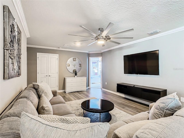 living room with ceiling fan, a textured ceiling, light hardwood / wood-style flooring, and crown molding