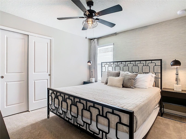 carpeted bedroom with a textured ceiling, ceiling fan, and a closet