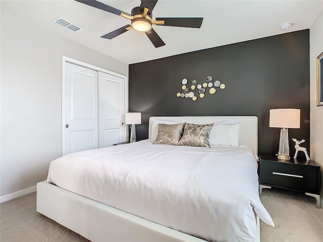 bedroom with ceiling fan, light colored carpet, and a closet