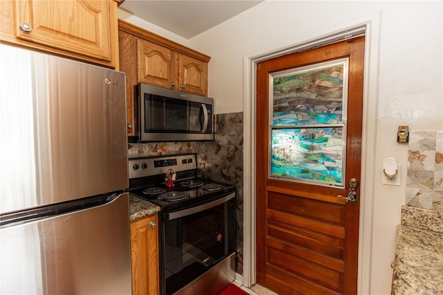 kitchen with light stone countertops, backsplash, and appliances with stainless steel finishes