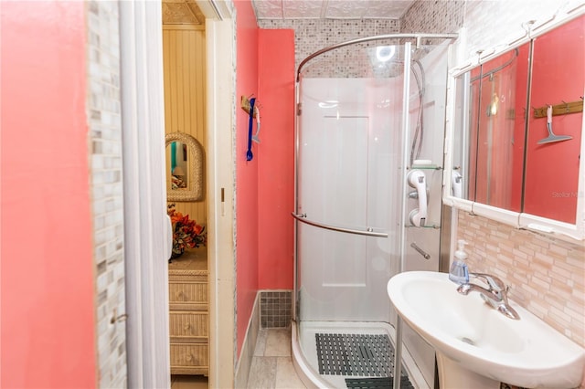 bathroom featuring a shower with shower door, sink, tasteful backsplash, and tile patterned flooring