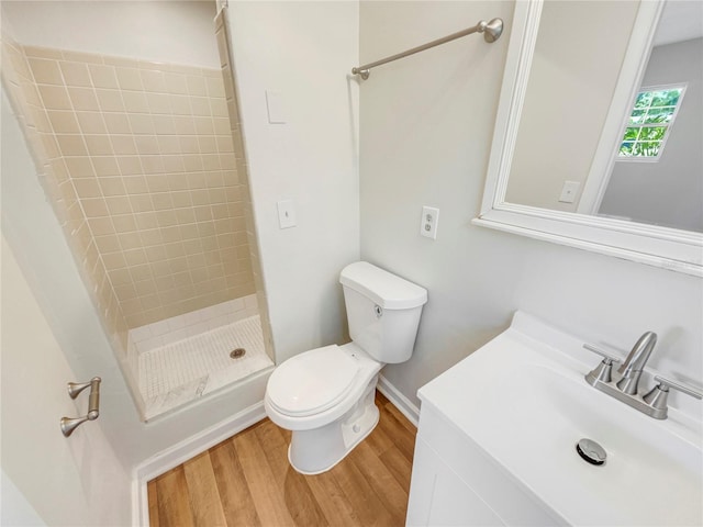 bathroom featuring vanity, hardwood / wood-style flooring, toilet, and tiled shower