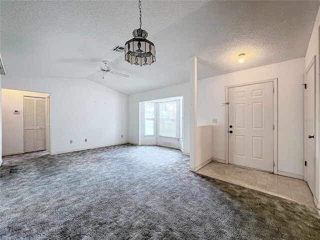 foyer entrance with ceiling fan, carpet flooring, a textured ceiling, and vaulted ceiling