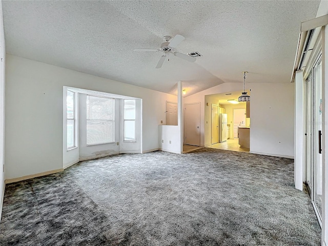 unfurnished living room with carpet, vaulted ceiling, ceiling fan, and a textured ceiling