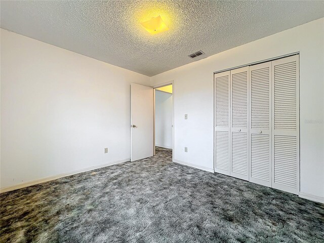 unfurnished bedroom with a textured ceiling, carpet flooring, and a closet