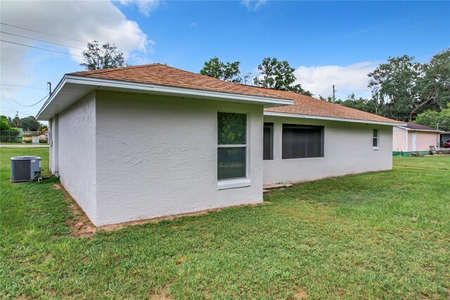 rear view of house with a lawn and central AC unit