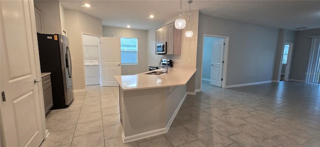 kitchen with hanging light fixtures, sink, kitchen peninsula, stainless steel appliances, and washer / dryer