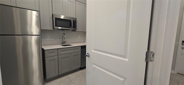 kitchen with gray cabinets, appliances with stainless steel finishes, light tile patterned flooring, and sink