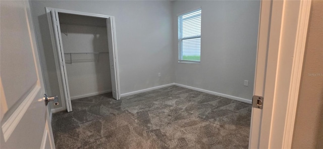 unfurnished bedroom featuring dark colored carpet and a closet