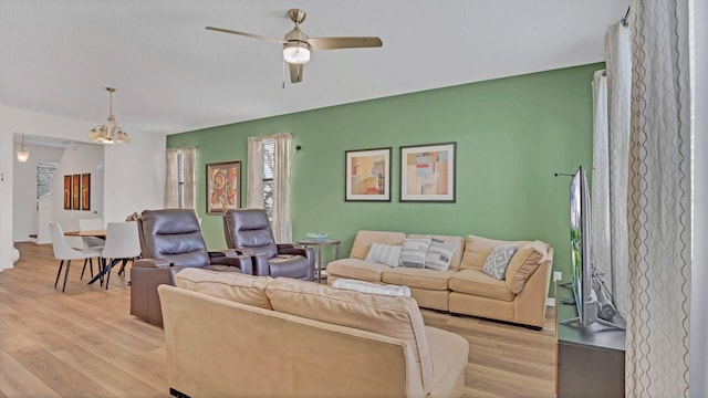 living room featuring ceiling fan with notable chandelier and light hardwood / wood-style floors